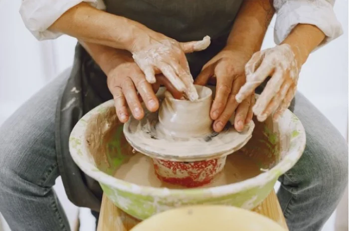 Mutual creative work. adult elegant couple in casual clothes and aprons. people creating a bowl on a pottery wheel in a clay studio.